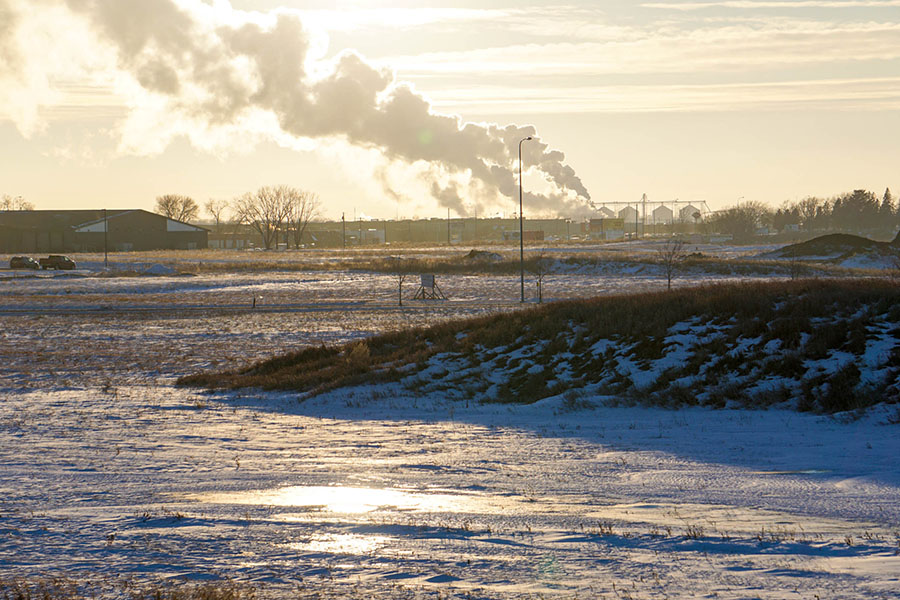 Contractor Insurance - Landscape of Factory in South Dakota with Smoke in the Distance and Snow and Ice on the Ground