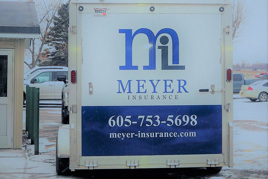 Business Owners Insurance - Meyer Insurance Logo with Contact Information Printed on the Back Door of a Commercial Truck Parked in a Parking Lot on a Snowy Winter Day